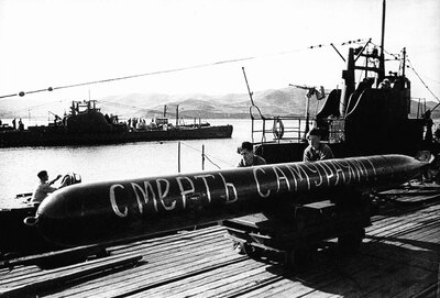 Погрузка торпеды на подводную лодку V-бис серии. Вместо кормового орудия на корабле установлен пулемет ДШК. На заднем плане «Щука» X серии. Август 1945 г.